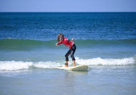 A child is standing up on the board during the surfing lessons for kids in la pointe de la torche for all levels with ESB la torche.