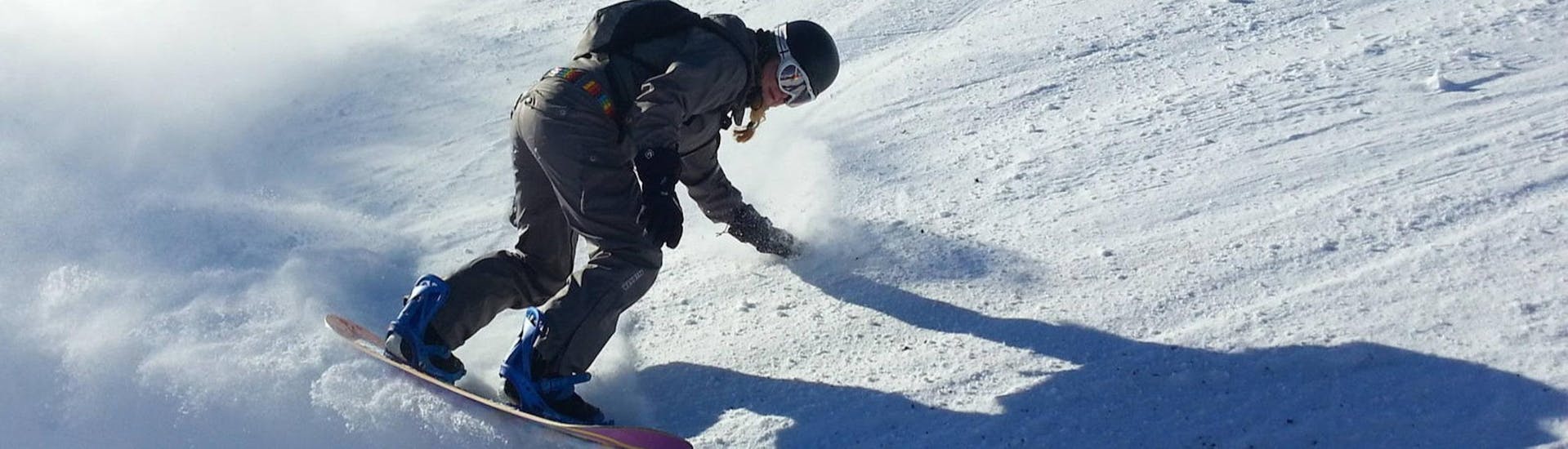 Eine junge Snowboarderin zieht bei ihrem Snowboardkurs für Kinder und Erwachsene mit der Skischule Schwarzenberg am Bödele ihre Spuren auf einer frisch präparierten Piste.