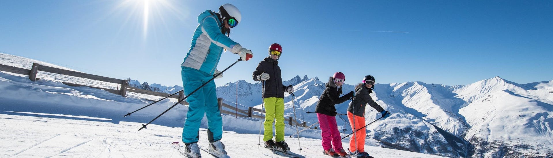 Un moniteur de ski de l'école de ski ESI Alpe d'Huez - European Ski School montre aux participants les bons gestes pendant leur Cours de ski Enfants (6-12 ans) pour Tous niveaux.