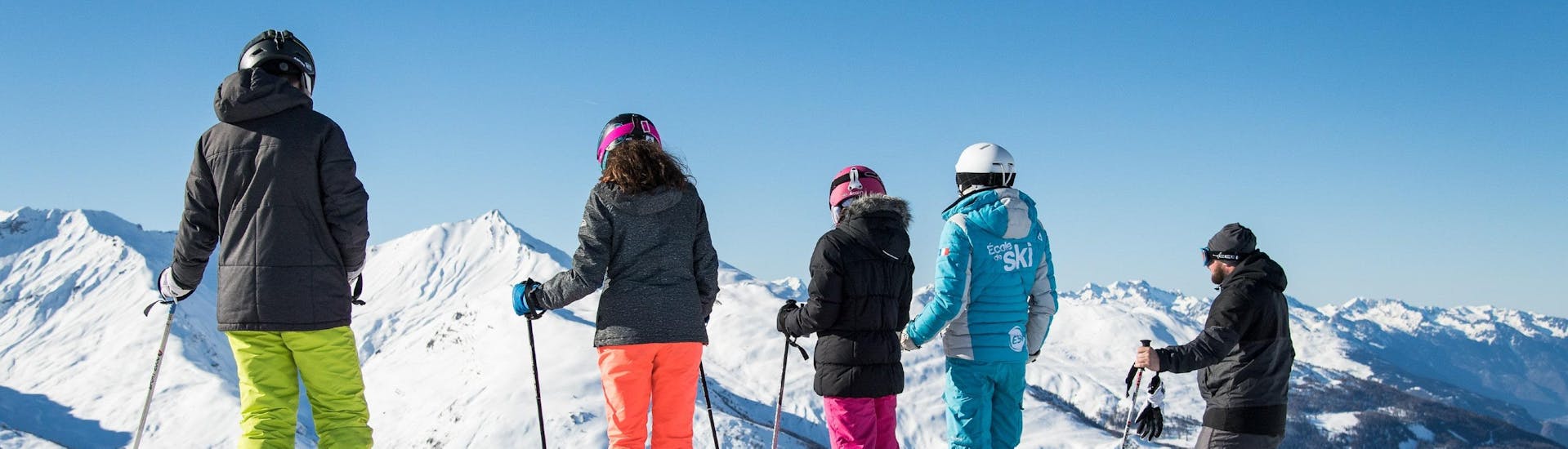 Des participants au Cours de ski Adultes pour Tous niveaux se préparent à descendre une piste avec leur moniteur de ski de l'école de ski ESI Alpe d'Huez - European Ski School.