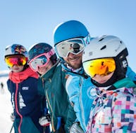 Kinder posieren um ihren Skilehrer von der ESI Alpe d'Huez - European Ski School während des privaten Skikurses für Kinder aller Levels.