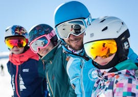 Los niños posan alrededor de su instructor de esquí de ESI Alpe d'Huez -European Ski School durante sus clases particulares de esquí para niños de todos los niveles.