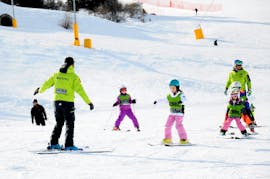 A group of small kids is practicing their first turns on skis during their Kids Ski Lessons (3-5 y.) - Christmas with the Maestri di Sci Cristallo Monte Bondone.