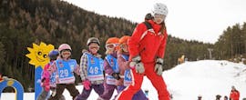 Eine Gruppe junger Kinder fährt bei ihrem Kinder-Skikurs (5-16 J.) für Anfänger hinter der Skilehrerin der Skischule Schaber in Grünberg Obsteig die Piste hinunter.