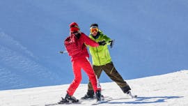 A ski instructor from Skischule Schaber in Grünberg Obsteig is helping a young man keep his balance on skis during his Private Ski Lessons for Adults of All Levels.