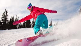 Eine Snowboarderin in einer pinken Jacke und einer grünen Hose zieht beim Privaten Snowboardkurs für Kinder & Erwachsene aller Levels mit der Skischule Schaber in Grünberg Obsteig ihre Spuren im Schnee.