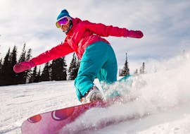 A snowboarder dressed in a pink jacket and green trousers can be seen drawing their tracks in the snow during their Private Snowboarding Lessons for Kids & Adults of All Levels with Skischule Schaber in Grünberg Obsteig.
