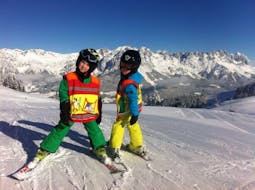 Two children stand happily on the piste and are happy about their learning progress during their Private Ski Lessons for Kids (from 3 y.) of All Levels from Skischule Ingrid Salvenmoser.