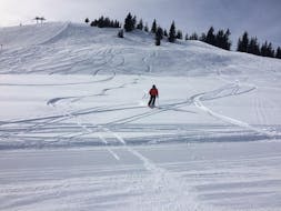 Een skileraar geniet van het skiën in diepe sneeuw met de privégids in Scheffau am Wilden Kaiser van de skischool Ingrid Salvenmoser.