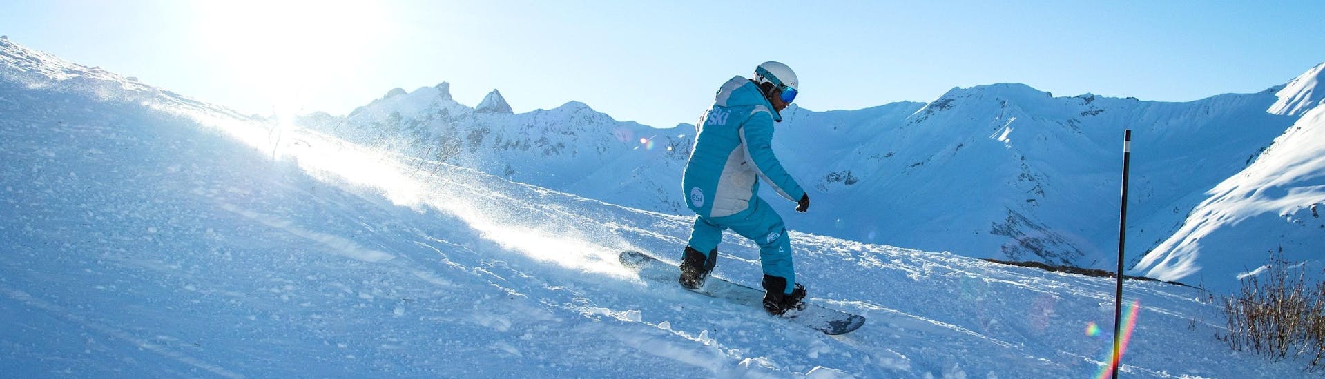 A snowboarder is sliding down a slope during his Private Snowboarding Lessons for All Levels - Morning with the ski school ESI Ski Family in Val Thorens.