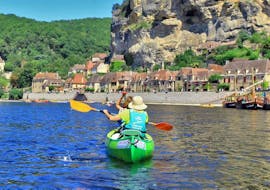 A woman wearing a hat paddles with her friends on the Dordogne River during the 16km journey from Vitrac with Canoë Dordogne.