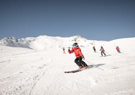 Ein Skilehrer der Ski- und Snowboardschule Vacancia eklärt bei der Aktivität Kinder Skikurs "All Inclusive" (4-8 Jahre) - Alle Levels einer Gruppe junger Skifahrer die Grundlagen des Skifahrens.