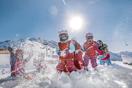 Un groupe de jeunes enfants s'amuse lors d'une bataille de boules de neige pendant leur cours de ski pour enfants Bambini (3-5 ans) pour débutants avec la Skischule Schruns.