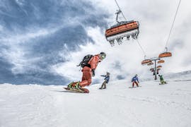 Eine Gruppe von Snowboardern übt beim Snowboardkurs für Erwachsene & Kinder (ab 6 J.) aller Levels mit der Hilfe eines erfahrenen Snowboardlehrers der Skischule Schruns das Kurvenfahren.