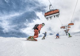 Eine Gruppe von Snowboardern übt beim Snowboardkurs für Erwachsene & Kinder (ab 6 J.) aller Levels mit der Hilfe eines erfahrenen Snowboardlehrers der Skischule Schruns das Kurvenfahren.