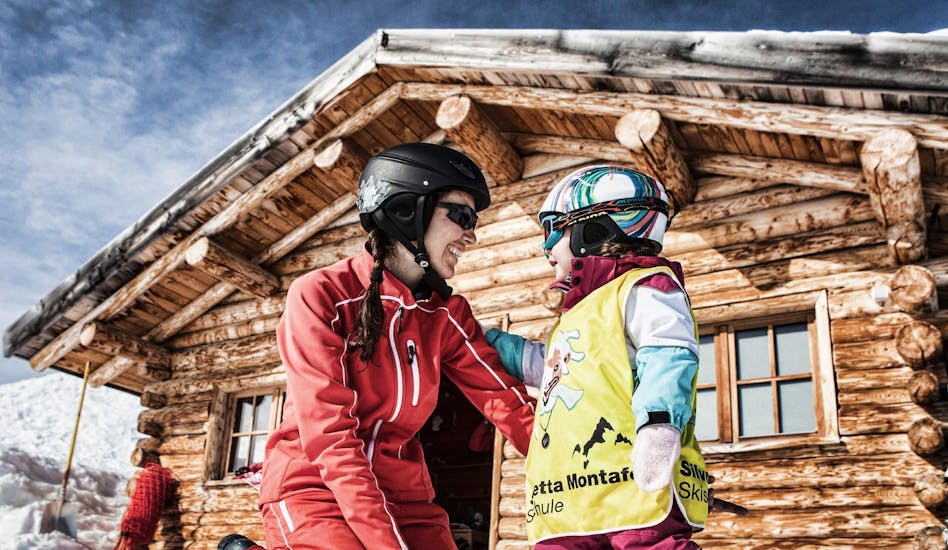 Een skileraar helpt een klein kind met zijn eerste ski-ervaring tijdens de privéskilessen voor kinderen van alle leeftijden met Skischule Schruns.