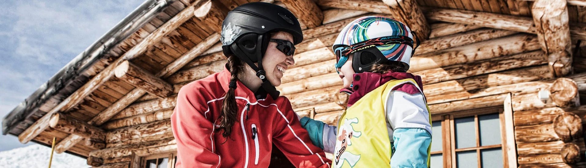Un moniteur de ski aide un petit à faire sa première expérience de ski pendant les cours particuliers de ski pour enfants de tous âges avec la Skischule Schruns.