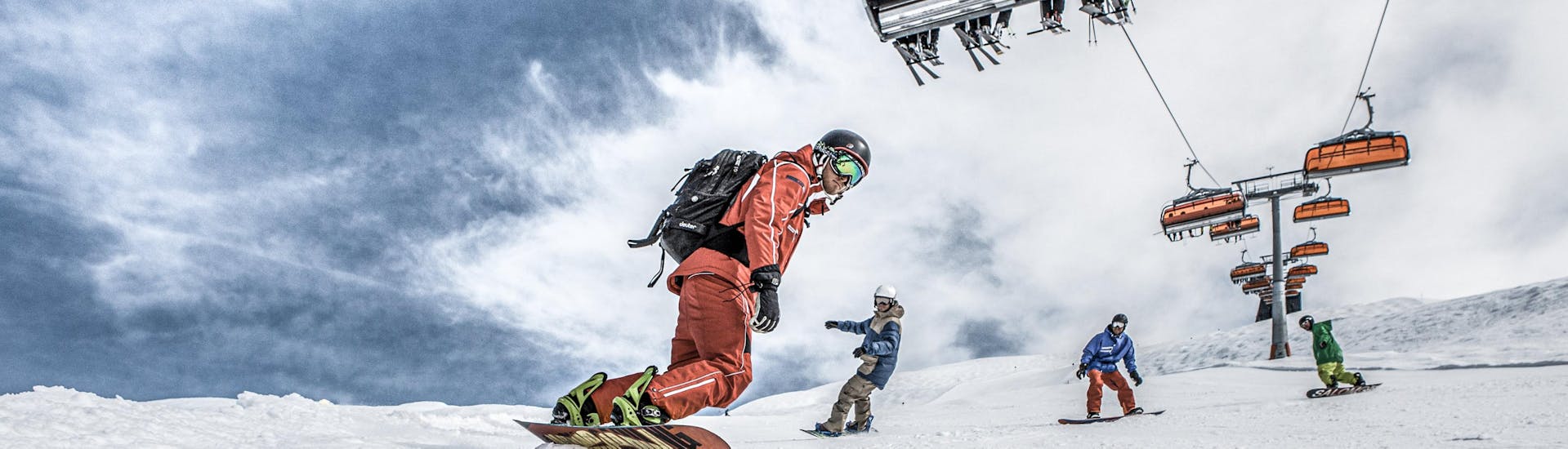 Trois amis explorent les pistes de la station de ski de Silvretta Montafon aux côtés d'un moniteur expérimenté pendant leurs cours particuliers de snowboard pour enfants et adultes de tous niveaux avec Skischule Schruns.