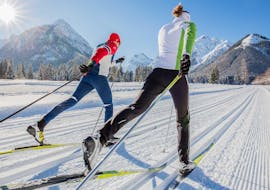 A man and a woman are gliding along the cross country track during their private cross country skiing lessons with ACT Sports Skischule in Arosa.