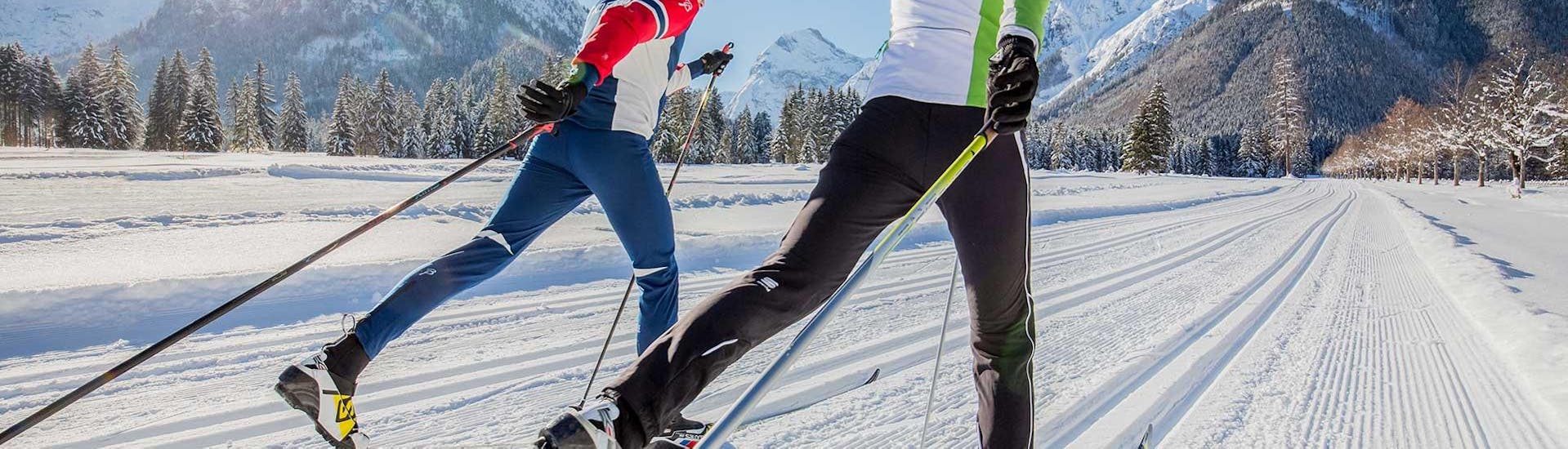 Un uomo e una donna scivolano sulla pista di fondo durante le lezioni private di sci di fondo con ACT Sports Skischule ad Arosa.