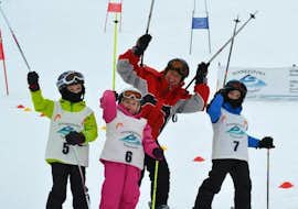Kinder-Skikurs (4 J.) für alle Levels - Ferien mit Schneesport Taberhofer Stuhleck Fröhliche Kinder winken der Kamera zu, während sie das Skifahren im Kinder-Skikurs für alle Levels (ab 4 Jahren) mit Schneesport Taberhofer am Stuhleck lernen.