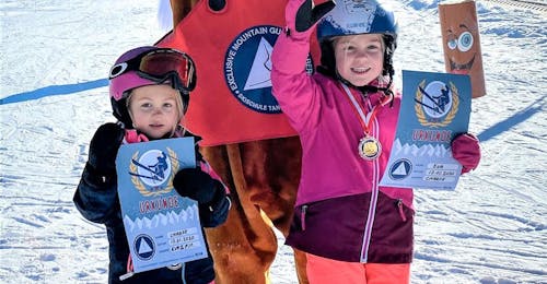 Ski Lessons for Kids & Teens (4-10 y.) of All Levels from Skischule Tannberg Lech Two young girls receive their medal and certificate from mascot Foxy after they completed their Kids Ski Lessons (from 4 y.) for All Levels with Skischule Tannberg Lech.