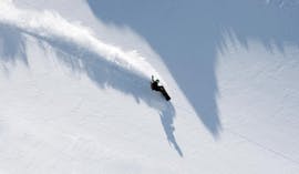 Uno snowboarder si esercita con nuove tecniche sulle piste durante le lezioni private di snowboard per bambini e adulti di tutti i livelli con Skischule Tannberg Lech.