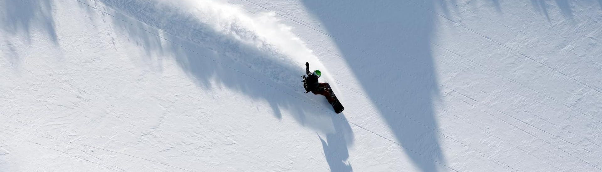 Een snowboarder oefent nieuwe technieken op de piste tijdens de privé-snowboardlessen voor kinderen en volwassenen van alle niveaus met Skischule Tannberg Lech.