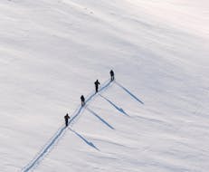 Un groupe de skieurs gravit la montagne enneigée avec le guide privé de ski et de splitboard pour Tous les Niveaux de Skischule Private Lech.