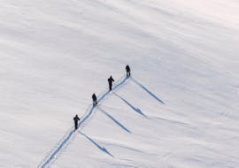 Un grupo de esquiadores está escalando la montaña nevada junto con la guía privada de esquí y splitboard para todos los niveles de Skischule Private Lech.