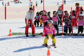 Un bambino si diverte molto con il suo gruppo di scuola di sci e il suo maestro di sci durante le lezioni di sci per bambini (3 anni) della Skischule Brunner a Bad Kleinkirchheim.