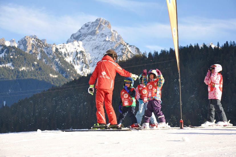 I bambini seguono le istruzioni del loro maestro di sci durante le lezioni di sci per bambini (dai 4 anni) per principianti della scuola di sci ESS Château d'Oex.