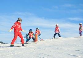 Kids are following their ski instructor to learn how to ski during their Kids Ski Lessons (from 4 y.) for Beginners with the ski school ESS Château d'Oex.