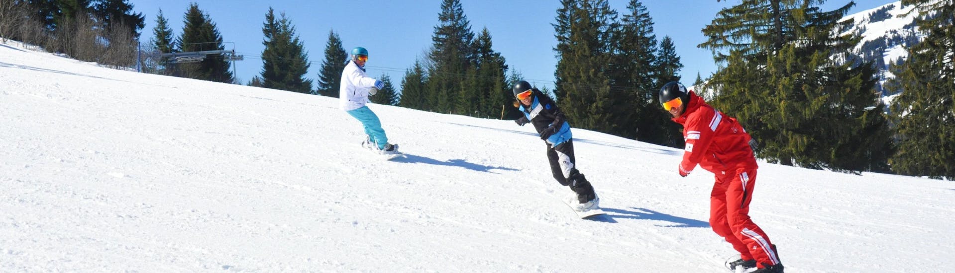 Snowboarders are following their snowboarding instructor on the slope during their Private Snowboarding Lessons for All Levels with the ski school ESS Château d'Oex.