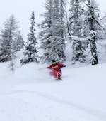 Ein Snowboardlehrer der Skischule Brunner in Bad Kleinkirchheim bringt einem Jungen das Snowboard fahren während des Snowboardkurses für alle Levels bei.