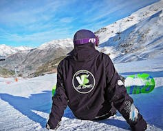 Ein Snowboardlehrer genießt das wunderschöne Panorama des Vall de Boí während des Snowboardkurses für Kinder und Erwachsene aller Levels.