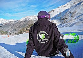 Ein Snowboardlehrer genießt das wunderschöne Panorama des Vall de Boí während des Snowboardkurses für Kinder und Erwachsene aller Levels.