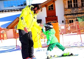 Un maestro di sci della scuola Maestri di sci Moena insegna a un bimbo come muovere i primi passi sulla neve durante le Lezioni di sci per bambini (3-5 anni) per principianti.