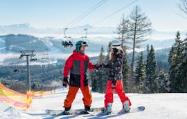 Two snowboarders enjoy their time together during the private snowboarding lesson for kids and adults of Skischule Obertraun in Dachstein Krippenstein.