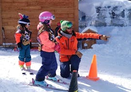 A ski instructor from the ski school Evolution 2 La Plagne Montchavin - Les Coches is giving advice to a young skier during her Kids Ski Lessons (4-5 y.) for First Timers.