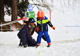 A ski instructor from the ski school Evolution 2 La Plagne Montchavin - Les Coches is helping a young skier finding his balance during his Private Ski Lessons for Kids of All Levels.