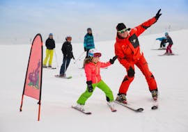 The ski instructor of Skischule Zahmer Kaiser teaches a kid how to ski during the kids ski lesson from 5 years for beginners.