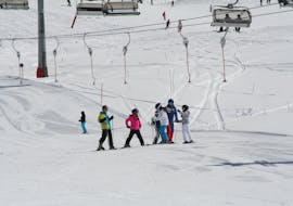 Un groupe d'enfants s'entraîne à skier sur la piste pendant leurs cours de ski pour enfants (6-15 ans) pour les skieurs expérimentés de la Skischule Ischgl.