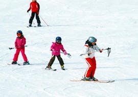 During the Private Ski Lessons for Kids of All Ages with Hansis Skischule Steinach am Brenner, three children are practicing their skiing skills with the help of an experienced instructor.