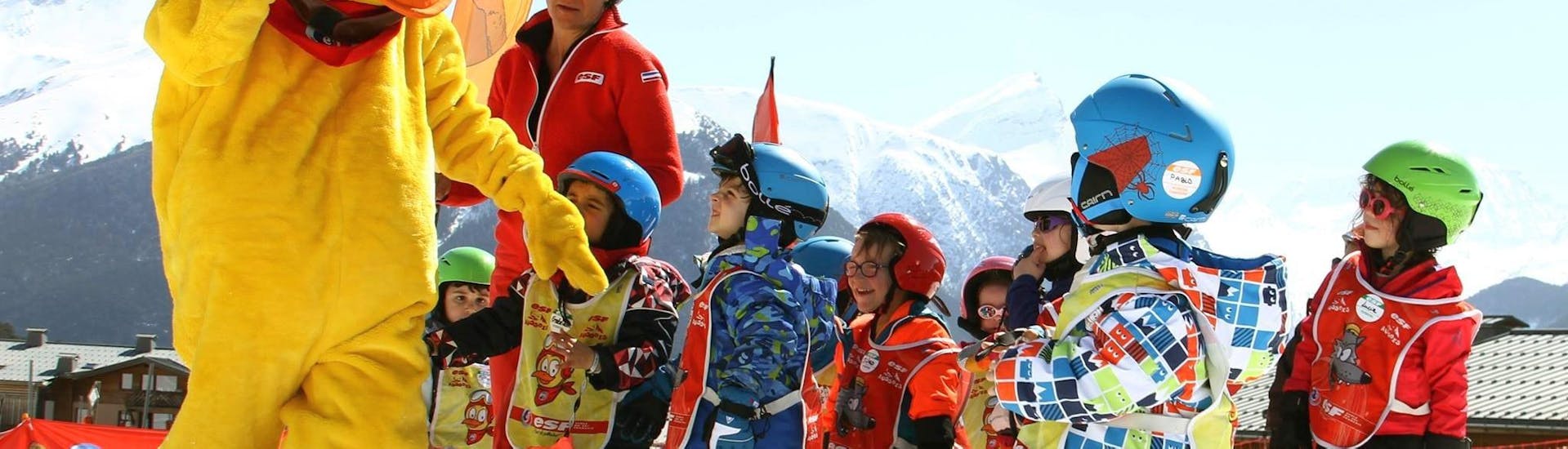Kids are happy to learn to ski with the mascot of the ski school ESF Aussois during their Kids Ski Lessons "Snow school" (2½-3 y.).