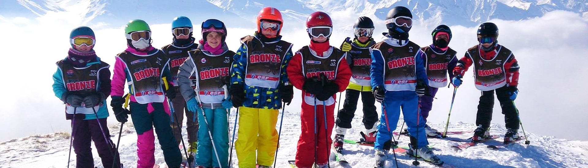 Kinderen maken een foto voor een besneeuwde achtergrond aan het einde van hun kinderskilessen (5-12 jaar) voor alle niveaus met de skischool ESF Aussois.