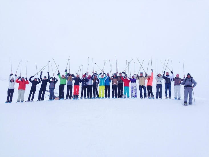 Los esquiadores, parados uno al lado del otro en la cima de una pista con los palos de esquí en el aire, esperando empezar sus clases de esquí para adultos (a partir de 14 años), de todos los niveles, con la escuela de esquí Evolution 2 Val Thorens.