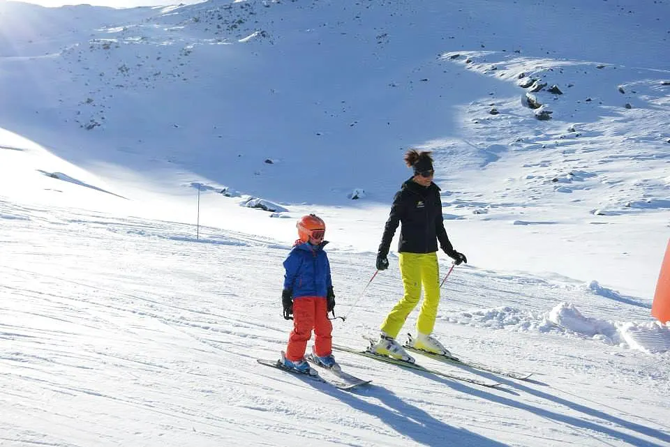 Cours particulier de ski Enfants (dès 4 ans) avec École de ski Evolution 2 Val Thorens Un moniteur de ski de l'école de ski Evolution 2 Val Thorens skie au côté d'un petit skieur pendant son Cours particulier de ski Enfants (dès 4 ans) - Vacances.