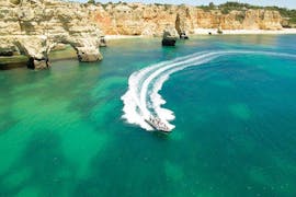 Un barco navega por la costa durante un viaje en barco a la cueva de Benagil desde Portimao con Seadventure Boat Trips Algarve.