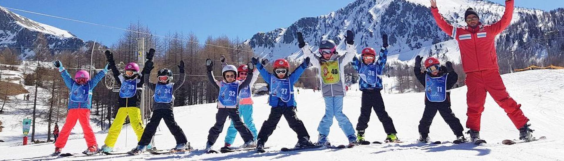 Les enfants sont debout les uns à côté des autres au bas d'une pente, heureux de commencer à apprendre à skier pendant leur Cours de ski Enfants (7-12 ans) pour Tous niveaux avec l'école de ski ESF Isola 2000.